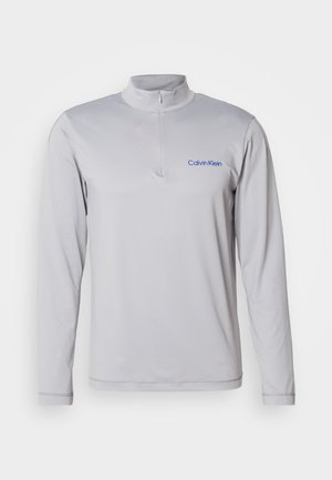 Dlhý rukáv, svetlosivý pulóver na zips s textúrovanou látkou. Na hrudi je modré logo Calvin Klein. Jednoduchý, atletický dizajn.