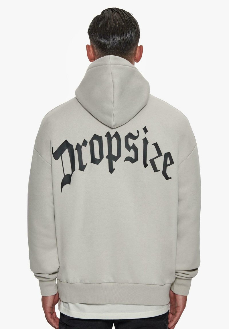 Hellgrauer Hoodie mit schwarzem "Dropsize"-Text auf dem Rücken. Er verfügt über eine geräumige Kapuze, lange Ärmel und einen gerippten Saum. Glatte Textur.