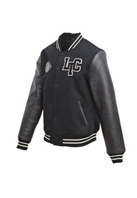 Schwarze College-Jacke mit einem Wollkörper und Lederärmeln. Weiß gestreifter ribbeliger Kragen und Bündchen, mit besticktem LTC-Logo und Aufnäher.