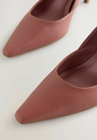 Ružové kožené slingback podpätky s špicatou špičkou a nízkym podpätkom, s hladkou textúrou a otvorenými stranami.