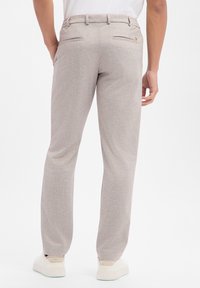 Jasnoszare, dopasowane spodnie z delikatną fakturą, z tylną kieszenią i szlufkami na pasek. Do tego białe trampki.