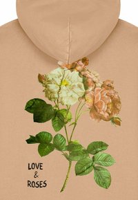 Felpa beige con un bouquet illustrato di rose bianche e rosa con foglie verdi. Sotto, il testo nero recita "AMORE & ROSE."