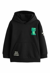 Sudadera negra con un bolsillo frontal, con un diseño de creeper pixelado verde y texto blanco que dice "¡CONSTRUYE, CREA, EXPLORA!" en el lateral.