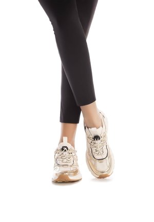 Zapatillas de correr de color claro con materiales de malla y sintéticos. Cuenta con cordones y una suela texturizada, combinadas con leggings negros.