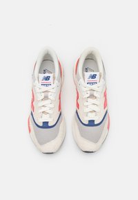 Tenisky v bílé, šedé a korálové barvě s vrchní částí z jemné síťoviny, akcenty z prošívané kůže a modrým logem. Mají bílé tkaničky a strukturovanou podrážku.