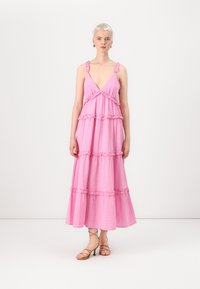 Pink maxi dress with ruffled straps and tiered design. Made of lightweight fabric, featuring a flowing silhouette and textured pattern.