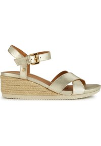 Sandal in metallo dorato con zeppa a cuneo, arricchita da fascette incrociate, fibbia alla caviglia e zeppa rivestita in juta. Parte superiore liscia e suola ammortizzata per maggiore comfort.