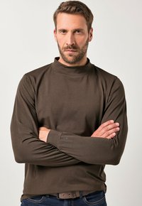 Brun langærmet turtleneck skjorte lavet af blødt stof, med en tætsiddende pasform og subtile stikninger på ærmerne.