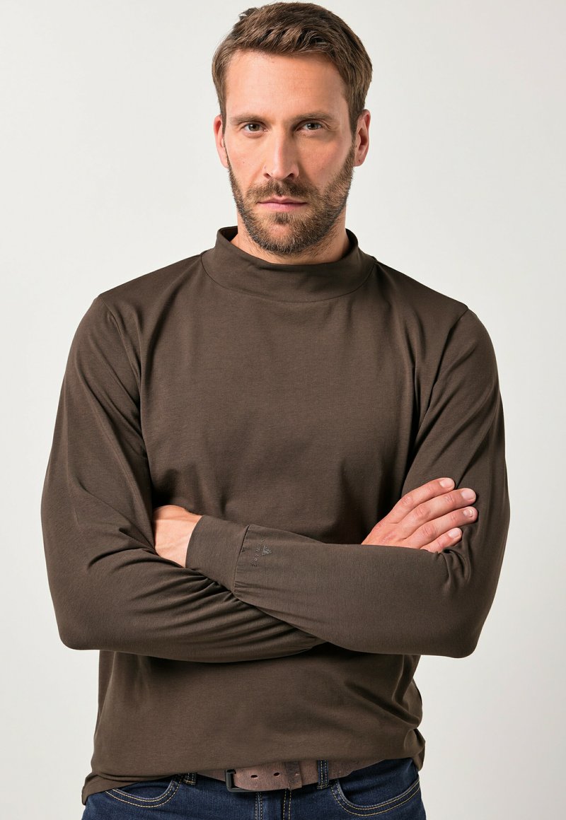 Brun langærmet turtleneck skjorte lavet af blødt stof, med en tætsiddende pasform og subtile stikninger på ærmerne.