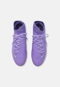 Zapatos de fútbol de tela púrpura con textura en espiral, suela de goma y logo de Nike en verde claro. Presenta un sistema de cordones tradicional.