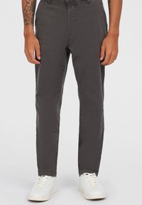 Grå, slim-fit bukser lavet af letvægtsstof, med en glat tekstur og knaplukning, parret med hvide sneakers.