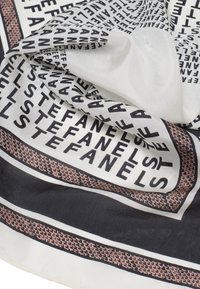 Pañuelo de seda con un patrón geométrico en blanco y negro en el que se repite la palabra "STEFANEL", bordeado por líneas contrastantes en azul marino profundo y beige claro.