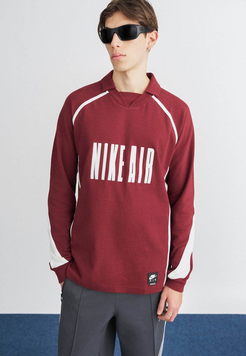 Sweatshirt bege com detalhes brancos, apresentando um grande logo "NIKE AIR". Manga longa e um corte descontraído, feito de material suave.