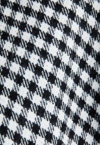 Čierno-biela tkanina s kostkovaným vzorom houndstooth a štruktúrovaným povrchom, pozostávajúca z kombinácie vlny a syntetických vlákien.