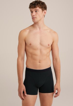Boxer shorts noirs en tissu texturé, avec une taille noire ornée d'un fin accent blanc, design ajusté et longueur mi-cuisse.