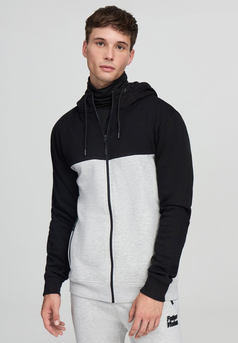 Felpa zip con cappuccio nera e grigia con colletto alto, caratterizzata da una texture liscia, cappuccio con cordino e tasche laterali.