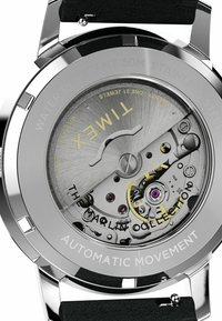 Zapięcie z nierdzewnej stali ze stalowym mechanizmem automatycznym; zawiera grawerowany tekst, widoczne tryby oraz purpurowe akcenty w mechanizmach wewnętrznych.