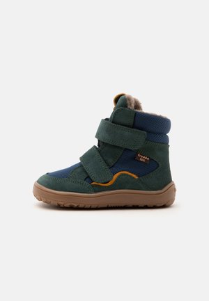 Botte d'hiver enfant vert foncé et bleu avec semelle marron, deux bandes auto-agrippantes, détails orange et doublure en polaire visible en haut.