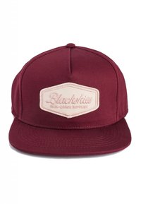Cappello bordeaux con visiera piatta, dotato di una toppa esagonale color crema ricamata con "Blackskies" e "High-Grade Supplies."
