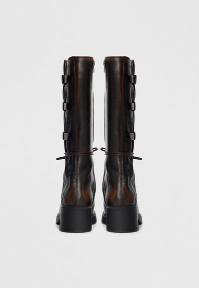 Black leather knee-high boots with side zip, lacing details, and a block heel. Smooth texture with contrasting brown accents.