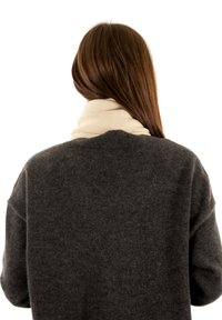 Pull en tricot gris avec une coupe ample, doté d'un col large, associé à une écharpe côtelée de couleur crème clair enroulée autour du cou.