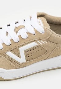 Tan ruskind sneakers med hvide snørebånd, der har et hvidt logo og detaljer, perforerede sektioner og en struktureret sål for godt greb.