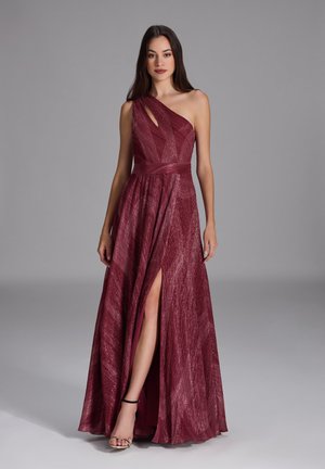 Robe une épaule bordeaux avec une fente diagonale, tissu texturé et taille cintrée. Présente une découpe sur le côté pour un détail supplémentaire.
