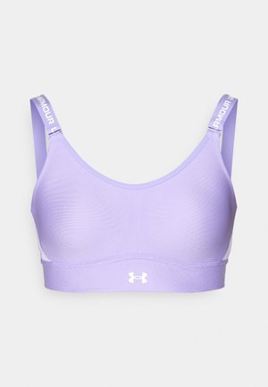 Ljubičasti sportski grudnjak izrađen od glatkog materijala, s širokim trakama na kojima se nalazi tekst "ARMOUR" i bijelim logotipom na prednjem rubu.