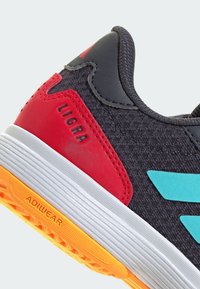 Grijze sportieve schoen met rode en turquoise accenten, gestructureerde bovenkant, ronde neus, witte tussenzool en een oranje rubberen buitenzool met profiel.