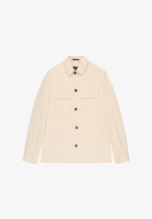 Giacca color crema con bottoni, due tasche con patta sul petto e maniche lunghe, mostrata distesa su uno sfondo bianco.