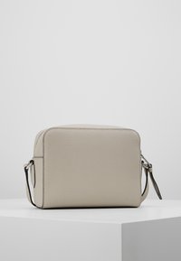 Borsa a tracolla in pelle beige con finitura testurizzata, forma rettangolare, chiusura superiore con cerniera e tracolla rimovibile. Design minimalista.