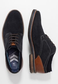Chaussures en suède bleu foncé avec des accents en cuir marron et des coutures contrastées. Dotées d'un bout arrondi et d'une semelle en caoutchouc, taille 41.