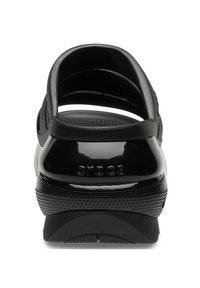 Sabots Crocs noirs avec un dos fermé, des surfaces texturées et lisses, et des perforations pour la ventilation. Nom de la marque embossé sur le talon.