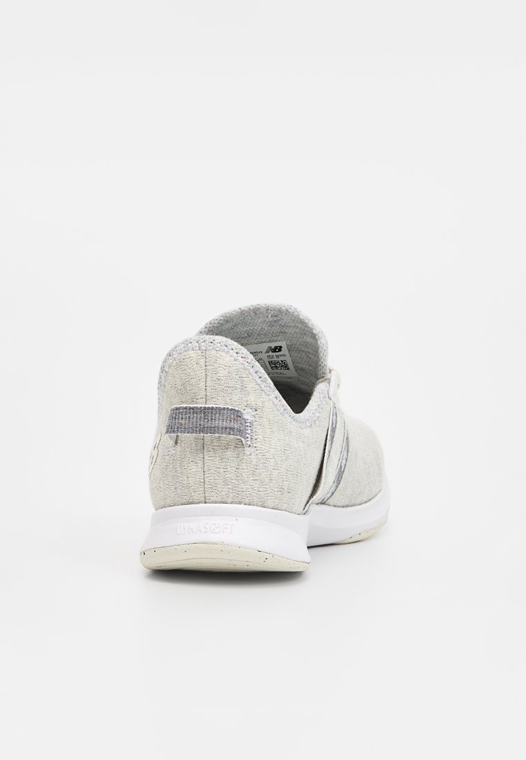 Chaussure de sport gris clair avec une tige en tissu texturé, semelle blanche et un petit onglet au talon. Elle présente un design simple avec des accents minimaux.