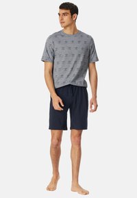 Grijze T-shirt met patroon en ronde hals, gecombineerd met marineblauwe shorts. Het T-shirt heeft een repetitief bedrukt ontwerp. Casual stof, ontspannen pasvorm.