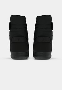 Bottes isolées noires avec une tige rembourrée et une sangle Velcro ajustable. Semelle en caoutchouc texturée avec le nom de la marque embossé à l'arrière.