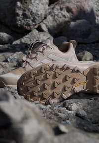 Beige sportssko med en struktureret overdel, snørebånd og markant slidbane på sålen. Har Continental-branding på ydersålen.