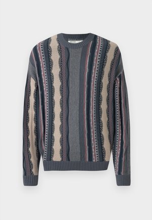 Strikkegenser med rund hals, med vekslende striper i marineblått, kremhvitt og rødt. Strukturerte mønstre med ribbestrikkede mansjetter og kant.