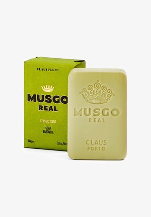MUSGO REAL Seife in hellem Gelb, rechteckiger Form mit eingeprägter Krone und Text. Die Verpackung ist grün mit schwarzer Beschriftung und Details zum Duft.