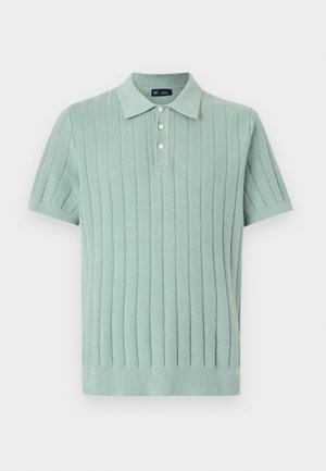 Polo manches courtes vert clair avec côtes verticales texturées et trois boutons blancs sur la patte de boutonnage avant.