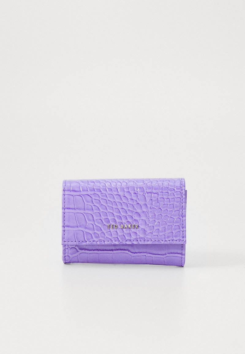 Portafoglio in pelle di colore lavanda con texture a coccodrillo e logo dorato "Ted Baker" sulla patta frontale, mostrato chiuso su uno sfondo bianco.