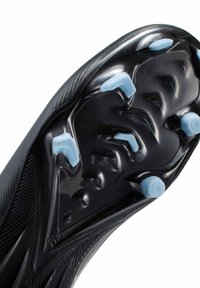 Semelle noire de chaussure de football avec six crampons moulés bleu pâle disposés pour la traction sur surfaces en herbe.