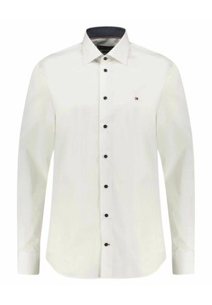 Biała, długa koszula z guzikami na całej długości, z czarnymi guzikami oraz małym haftowanym logo na lewej piersi.