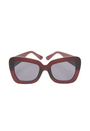 Czerwone, oversize okulary przeciwsłoneczne w szerokim kształcie cat-eye, wykonane z gładkiego plastiku. Ciemne soczewki i subtelne srebrne akcenty na zawiasach.