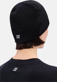 Zwart gebreide muts met een gladde textuur, voorzien van een klein grijs logo aan de achterkant. Aansluitend ontwerp, geschikt voor koud weer.