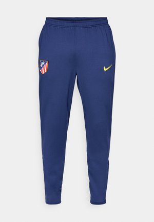 Merineeritud sportlikud püksid, mis on valmistatud kergest kangast, koos kollase Nike logo ja punase ja valge triibuga klubiembleemiga. Kokkupandav elastne vöökoht.