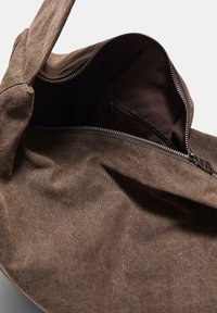 Brun stoftaske med lynlås. Indvendigt er der en lille lynlåslomme. Blød tekstur, afslappet design.