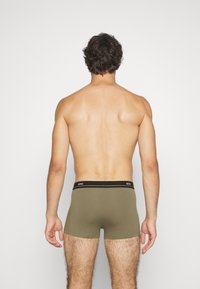 Boxers de color verde oliva con una cinturilla de logo negra, con un diseño ajustado y material suave, vistos desde la parte posterior.