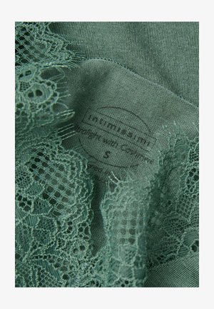 Ciemnozielony materiał z misternym koronkowym wykończeniem i miękką teksturą, z widoczną metką z napisem "Intimissimi" oraz rozmiarem 'S'.