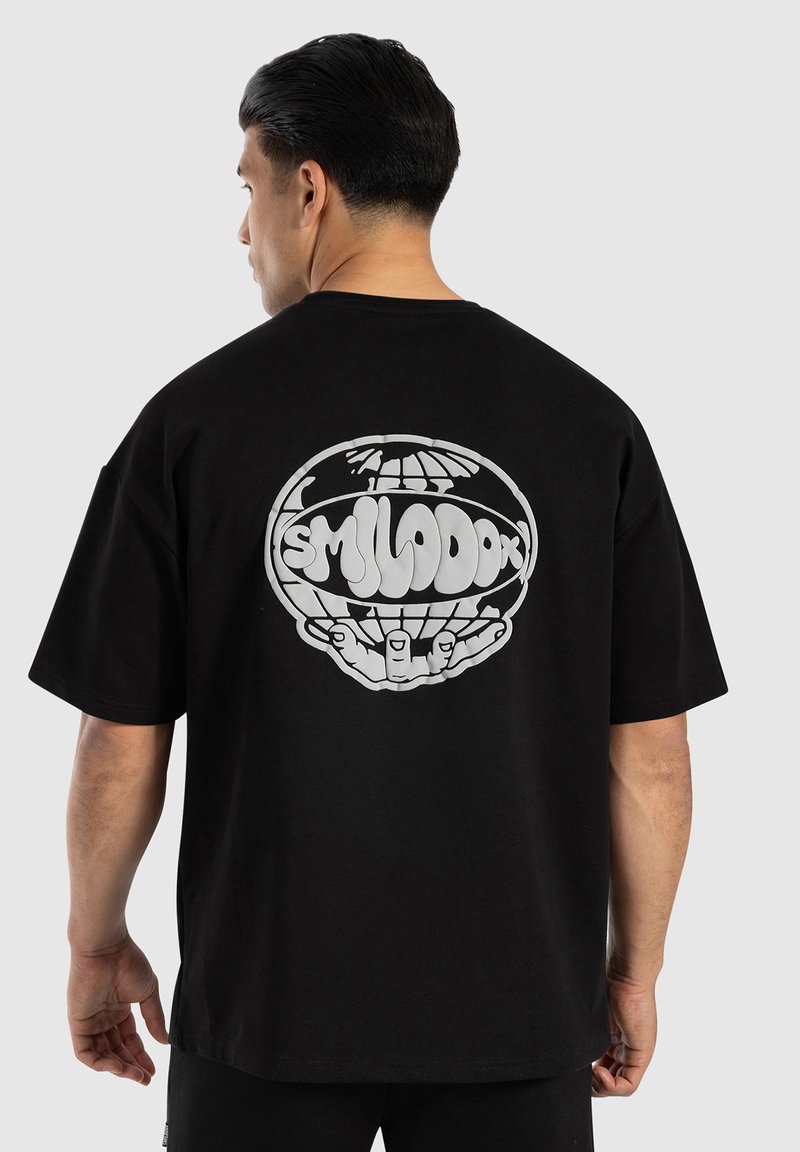 Camiseta de algodón negra con mangas cortas, que presenta un gran gráfico blanco de un globo y manos en la parte posterior. Diseño simple, ajuste relajado.